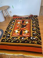 Full view of the rectangular geometric abstract rug laid out on wood floor, highlighting the vibrant color scheme and pattern with fringed edges.