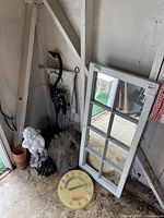 Photo shows the wall mirror leaning against the wall, white garden statue, plant pots stacked, round thermometer on ground, and black metal water pump beside the statue.