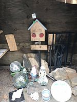 Photo showing entire lot of garden decor including wooden welcome sign, metal wall art, rock stepping stones, disco balls, planter, and garden statues.