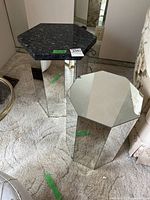Two hexagonal side tables; one with a black marble top and mirrored glass base, the other fully mirrored glass.