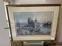 Framed print showing a cabin, a person, and a natural outdoor scene under cloudy sky.