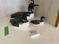 Three loon decoy figurines displayed on a table, showing varied sizes and detailed paintwork.