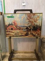 Front view of one tray table showing scenic autumn landscape design with barn and well, mounted on metal folding legs.
