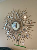 Full view of the sunburst decorative wall mirror with a central round mirror and multiple smaller circular mirrors on metal rays.