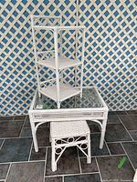 White wicker three-tier shelf, glass-topped wicker table, and square wicker stool set against blue and white lattice background. Highlights size and condition.