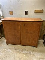 Front view of wooden cabinet with closed double doors and smooth top surface.
