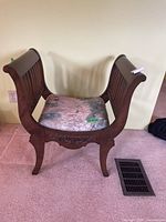 Front view of wooden U-shaped chair showing curved legs, upright slatted back and sides, upholstered seat with botanical fabric.