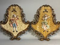 Pair of vintage Italian Baroque style framed wall plaques with 3D relief figures of Victorian man and woman, showing full front view.