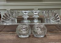 Front view of all three pairs of candleholders including Rosenthal Blossom, Iittala Festivo, and Kosta Boda snowball sets, arranged on table