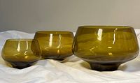 Side view of three amber glass nesting bowls showing varying sizes and footed bases