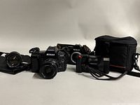 Full lot arrangement showing Nikon F90X with lens, Nikon N2000, Pentax AF camera, lenses, and carrying cases.