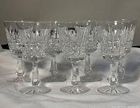 Seven Waterford cut crystal wine glasses arranged in rows on a white cloth background, showing front and side profiles.