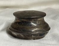 Closed view of the tarnished antique sterling silver jewelry box showing rounded shape and dents.