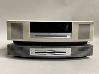 Front view of BOSE Wave Music System main unit in beige with multi-CD changer accessory in gray stacked below.