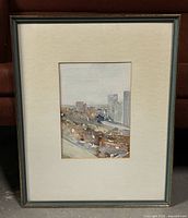 Full view of framed watercolour painting depicting an urban scene with muted tones under glass including white mat and simple gray frame