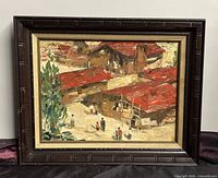 Framed oil painting on board depicting red-roofed village buildings and figures, showing overall condition and frame wear.