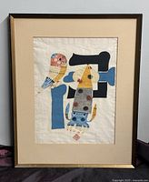 Framed print showing colorful marine life motifs with a squid and bird, and Japanese characters, in a dark wood frame with beige mat. Some nicks on the frame visible.