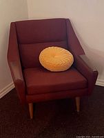 Front view of brick-red wool upholstered armchair with removable cushion and yellow pillow shown for scale (pillow not included).