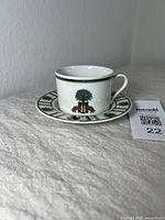 Front angle of the cup and saucer with the tree and animal design visible on the cup and saucer rim