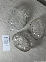Three antique glass jelly moulds placed on fabric, showing top and side views.