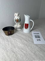 Photo showing the three items together: brass dish, ceramic owl, and ceramic pitcher with a lot number card beside them.