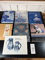 Set of 7 ceramic and porcelain reference and poetry books, arranged on a black table.