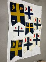 Eight vintage Royal Canadian Yacht Club flags laid out on white cloth, showing designs and varying conditions.