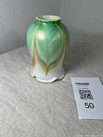 Side view of green feather pulled art glass lamp shade with ruffled top edge