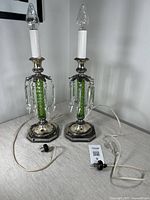 Pair of antique Pairpoint lamps showing full front view with bulbs in place and cords extending from bases.