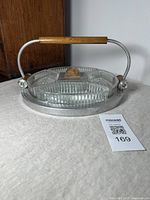 Front angled photo showing the entire Art Deco aluminum framed circular serving tray with wooden handle and five inset glass dishes.