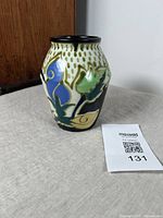 View of Art Deco Hongan Ware vase showing front floral pattern and brown dash background on white with black rim.