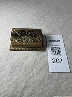 Closed view of brass stamp box with floral cutout lid and sunflower motif on top.