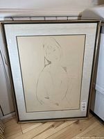 Framed lithograph print leaning against wall, showing full artwork and frame.