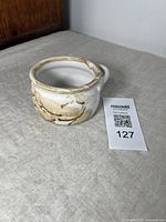 Pottery bowl by Jane Snider, showing front and top views with handle visible. Light glaze in beige and white tones.