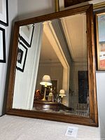 Full view of the large beveled mirror with oak frame showing reflective surface and visible oxidation spots.