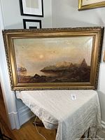 Full view of the large antique coastline painting in a carved gilt plaster and wood frame, showing overall condition and size.