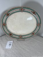 Full view of large oval stoneware platter with turquoise and brown geometric and cameo border design.