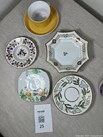 All items displayed together on fabric surface showing cup with yellow saucer, several decorative saucers and the octagonal dish.