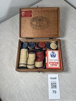 Open wooden cigar box containing several stacks of colored poker chips and a pack of EMU plastic coated playing cards.