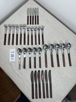 Complete set of cutlery pieces including forks, knives, and spoons laid on a fabric surface showing all items in the lot.