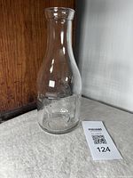 Front view of the glass milk jug on a cloth surface, showing its shape and embossed cow design on the side.