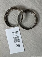 Two silver-rimmed crystal coasters shown top down, highlighting their round shape and silver rims.