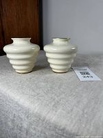 Side view of the pair of cream and gilt Carleton Ware vases showing ribbed Art Deco form and gilt trim.