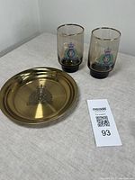 Photo showing brass tray and pair of amber glass tumblers together on a cloth surface.