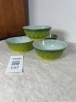 Photo showing four green glass bowls with Diamond Dot Beverly pattern exterior, displayed on a light surface with a lot tag.