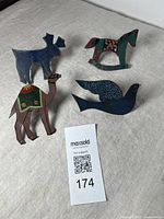Full set of four hand-painted animal napkin rings: blue moose, brown camel with green/red saddle, multicolor horse with floral motifs, and dark blue dove with patterned wings.