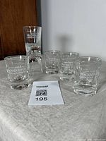 Six vintage MacNaughton Canadian Whisky double shot glasses arranged on a surface with two stacked and four in front.