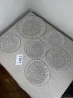 Set of five smaller and one larger Rosenthal crystal plates arranged on fabric surface.