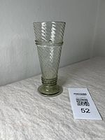 Clear blown glass vase with spiral twist and banded texture shown from a side angle on a cloth surface with lot tag 52.