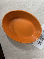 Top view of small orange oval Le Creuset casserole dish showing smooth interior and glossy finish.